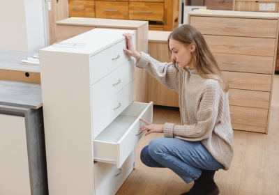 Young woman choosing cabinet with drawers in furniture store to buy