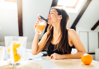 Woman at home drinking orange flavored amino acid vitamin powder