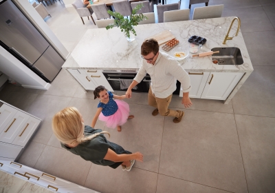 Family, children and dance with a girl and her parents dancing together in the kitchen of their home. Smile, fun and playful with a female child, her mother and father feeling happy in their house